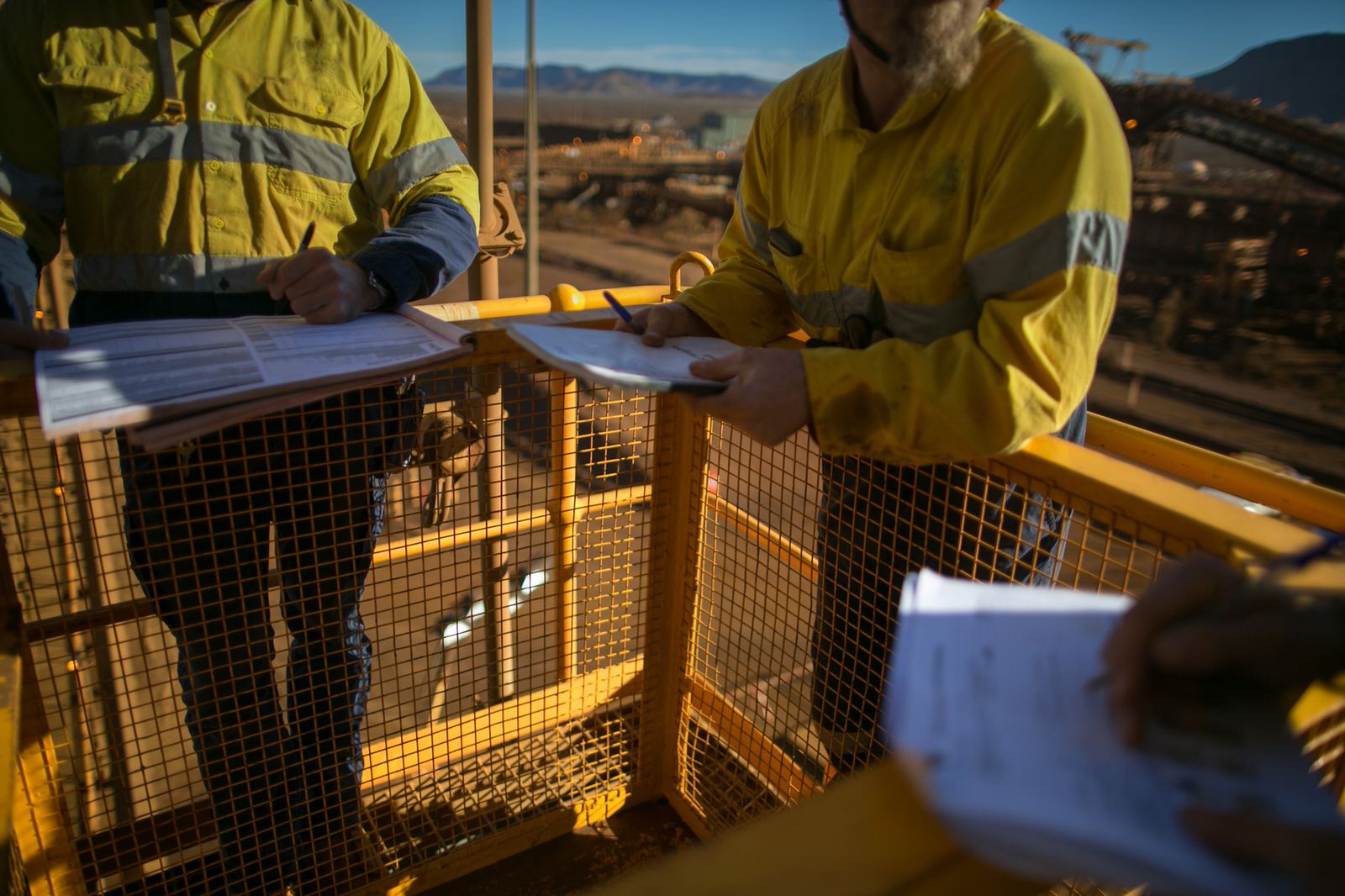 Workers in hi-vis checking permit paperwork on site, faces not shown