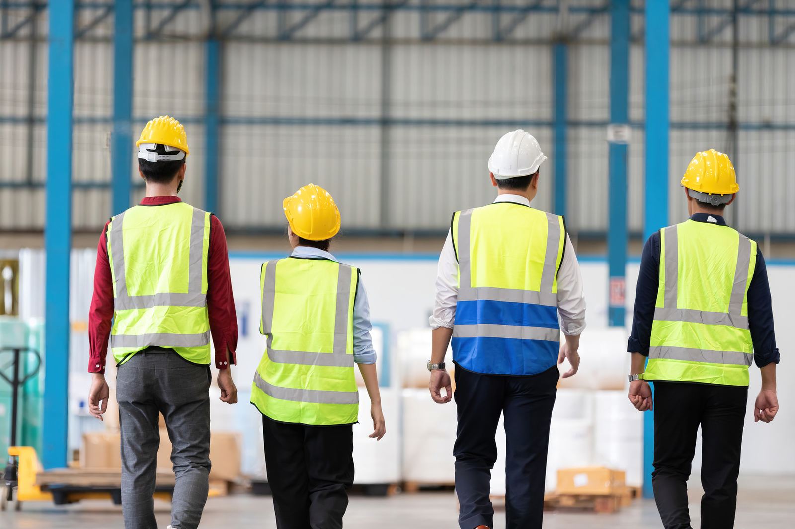 Workers in hi-vis walking in to start a shift, seen from behind